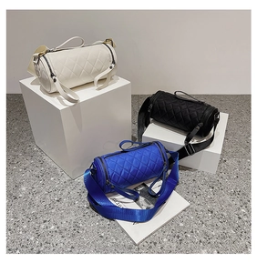 Three quilted cylinder crossbody bags in white, black, and blue on geometric stands