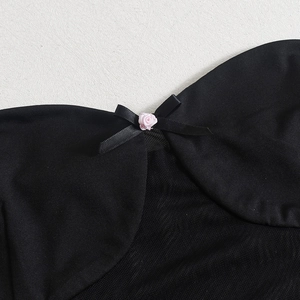 Détail de maille noire avec des touches de roses roses et un délicat nœud en ruban de soie