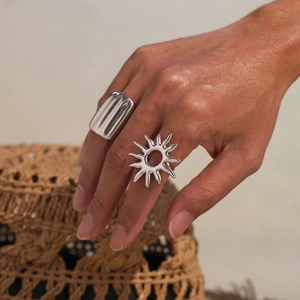 Polished silver wavy open ring and sun pattern cutout band on model's hand