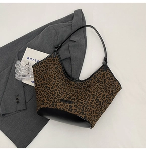 Flat lay of leopard print tote bag with brown canvas body and black faux leather details
