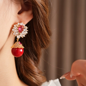 Détail d'une boucle d'oreille fleur vintage avec zircon rouge et cloche en métal sur modèle