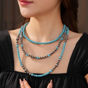 Dettaglio di una collana bohémien a tre strati con perline turchesi e argento su modella