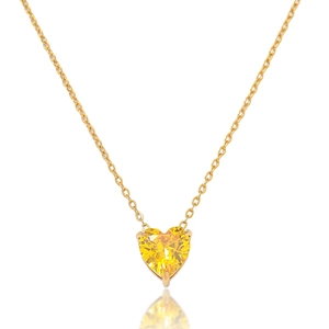 Macro detail of gold necklace with claw-set heart-shaped yellow faceted gemstone