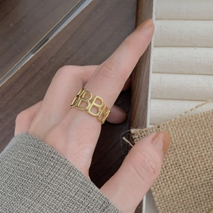 Detailed view of a gold-plated ring with a continuous hollow BB letter pattern
