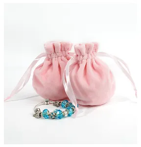 Detail of pink velvet drawstring pouches with a blue beaded charm bracelet and love engraving