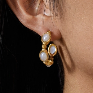 Elegant gold titanium earrings with white pearls on model with black background