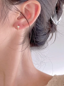 Detailed view of 925 silver pearl stud and minimalist gold ball earring on ear