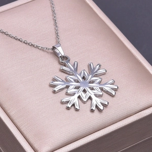 Macro shot of silver snowflake pendant necklace inside a luxury champagne jewelry box
