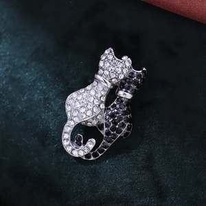 Macro shot of twin cat brooches with black and white rhinestones on green velvet
