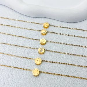 Detalle de seis colgantes dorados con caritas sonrientes, corazones y grabados de luna