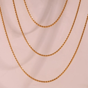Three-layered golden stainless steel box chain necklaces on a light pink background