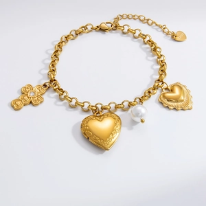 Detail of 18K gold plated stainless steel bracelet with cross, heart locket and pearl charms