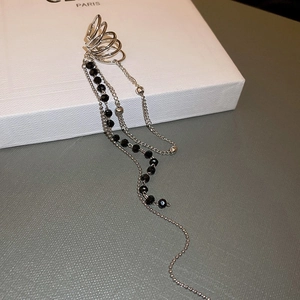 Détail du clip d'oreille argenté avec perles noires facettées et chaînes à pompons