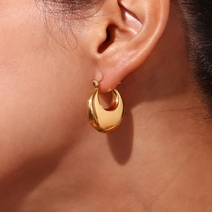Polished hollow 18K gold plated stainless steel oval earrings worn by a model