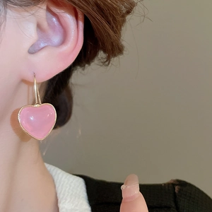 Pink heart resin drop earrings with gold metal frame worn by a female model