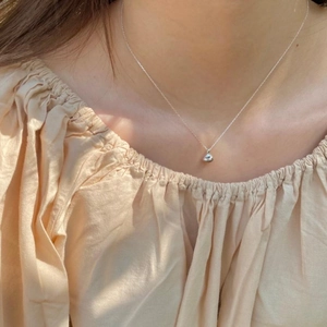 Close-up of a minimalist S925 sterling silver necklace with a teardrop pendant on model