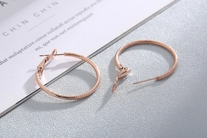 Detail of rose gold hoop earrings with fine spiral texture and polished metal finish
