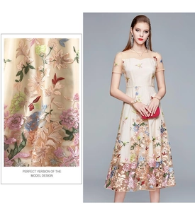 Detail of colorful floral embroidery and high waist design on a champagne tulle dress