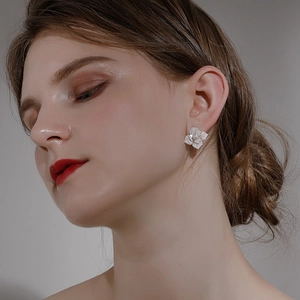 Detailed view of pearl-like camellia flower stud earring worn on model's ear