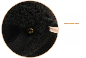 Gros plan sur la texture bouclée et les yeux en résine ambrée de la peluche mouton noir