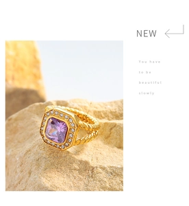 Detailed view of gold twisted ring featuring a purple square zircon on stone background