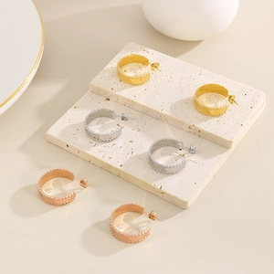18k gold plated irregular C-shaped hoop earrings with beaded edges on beige stone stand