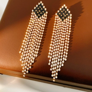Close-up of vintage geometric tassel earrings with white rhinestones on brown leather