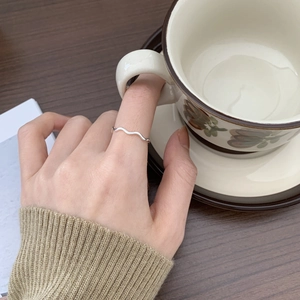Minimalist 925 sterling silver wavy ring worn on model finger with lifestyle background