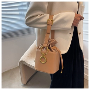 Chic beige drawstring bucket bag with metal ring accents styled with a white blazer outfit
