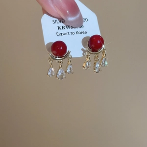 Detailed shot of red pearl earrings with teardrop zircons on a silver needle post