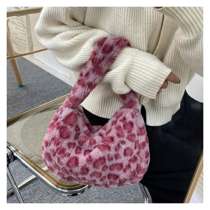 Close-up of pink leopard print faux fur handbag held by a model in a white cardigan