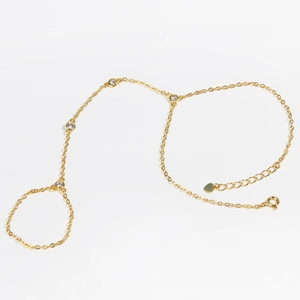 Detail of 18k gold chain hand harness with round diamonds and heart-shaped charm tag