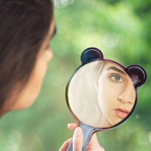 Outdoor shot of a black handheld makeup mirror with cute bear ears and ergonomic handle