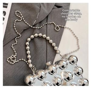 Detailed view of silver glossy spherical handbag with thick bead handle and chain strap