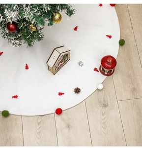 Vue détaillée du tapis de sapin de Noël blanc en feutre avec des sapins rouges et pompons