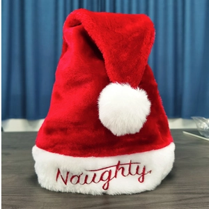 Détail du bonnet de Noël en peluche rouge avec bordure blanche et broderie Naughty