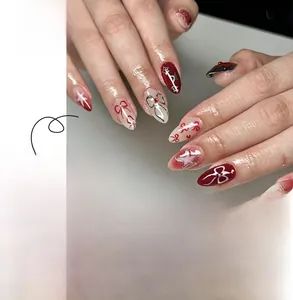 Detail of sweet bow and star press-on nails in burgundy and silver with glossy finish