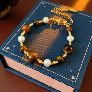 Detailed shot of tiger eye beads, pearls and gold spacers on a beaded bracelet