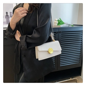 Détail d'un sac à bandoulière en cuir blanc avec un fermoir métallique doré rond