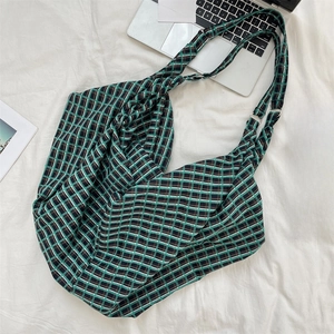 Detailed flat lay of green plaid tote bag showing metal strap buckles and soft fabric texture