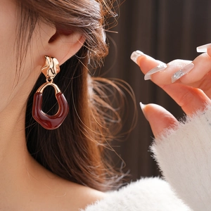 Close-up of model wearing chunky oval resin earrings with gold textured metal accents