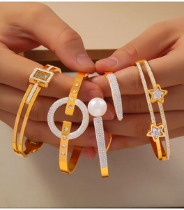 Detail of layered gold-plated titanium steel bangles with star and pearl accents
