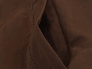 Macro shot of dark brown ribbed jacket pocket with detailed stitching and woven texture