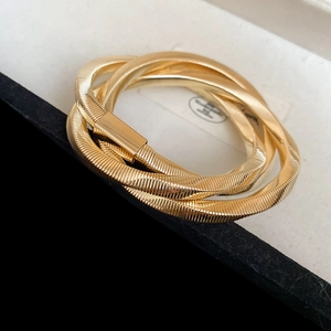 Detail of a triple-coil gold Tubogas bracelet with a sleek rectangular push-pull clasp