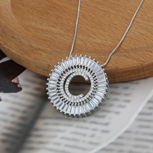 Detail of silver initial C pendant necklace with zircon crystals on a magazine