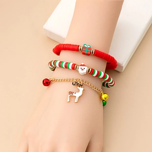 Close-up of Christmas charm bracelets featuring Santa, reindeer, and bells on a model's wrist