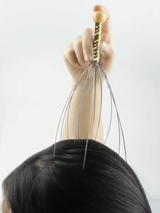 Detail van handmatige hoofdmassager met gouden antisliphandgreep en zachte massageklauwen