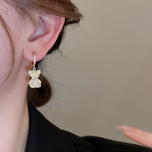 Gros plan d'un pendentif ours nacré avec boucle d'oreille zircon sur l'oreille