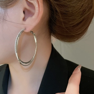 Close-up of sparkling silver rhinestone double-layered hoop earrings worn on ear