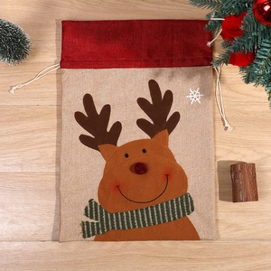 Christmas burlap drawstring gift bag with reindeer pattern on warm wooden background
